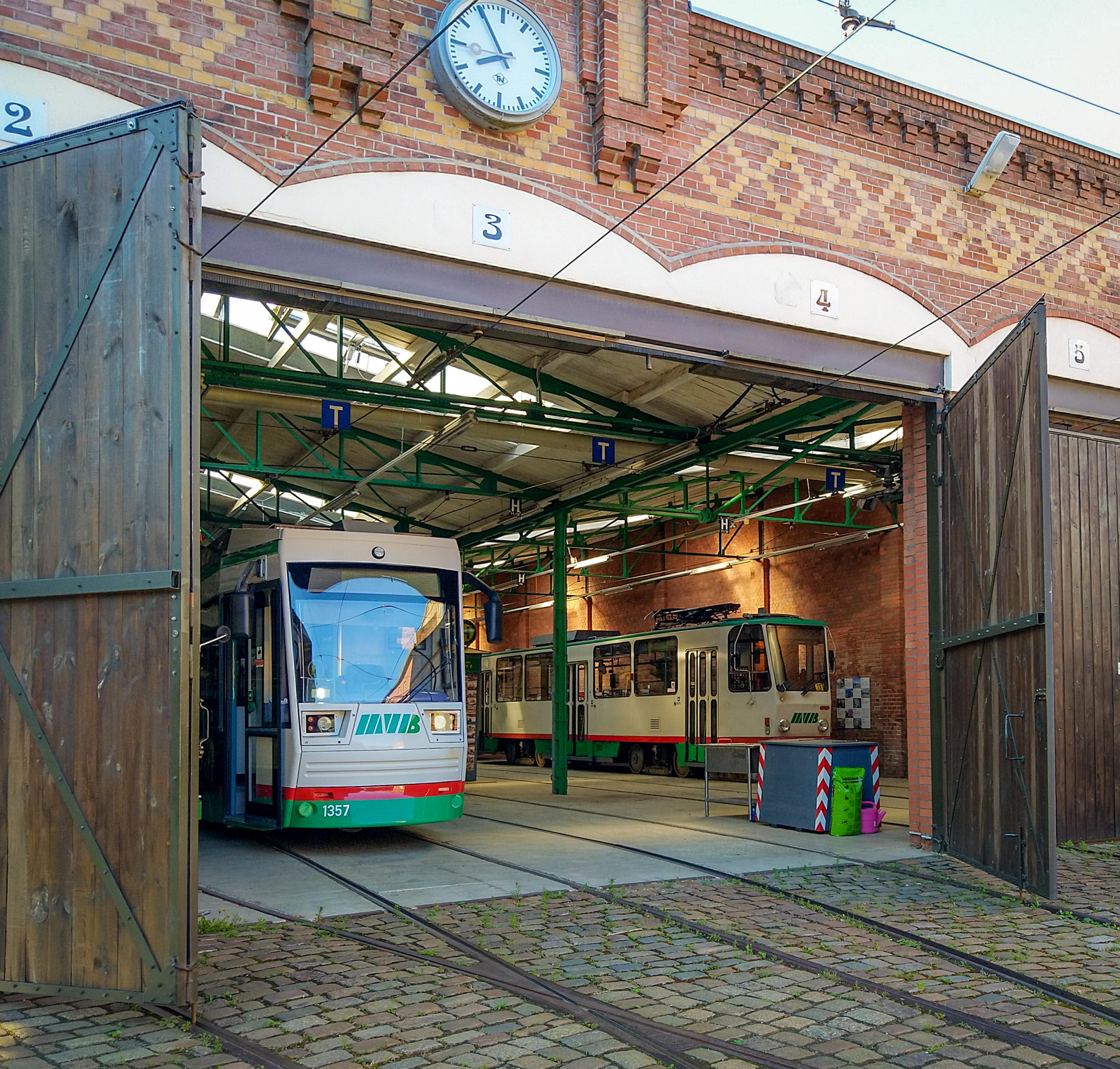 Das Depot Sudenburg mit geöffneten Toren, darin Straßenbahnen