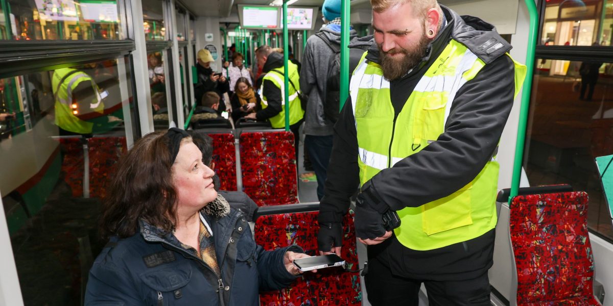 Ein freundlicher Mitarbeiter des Sicherheitsdienstes kontrolliert die Fahrscheine in der Straßenbahn.